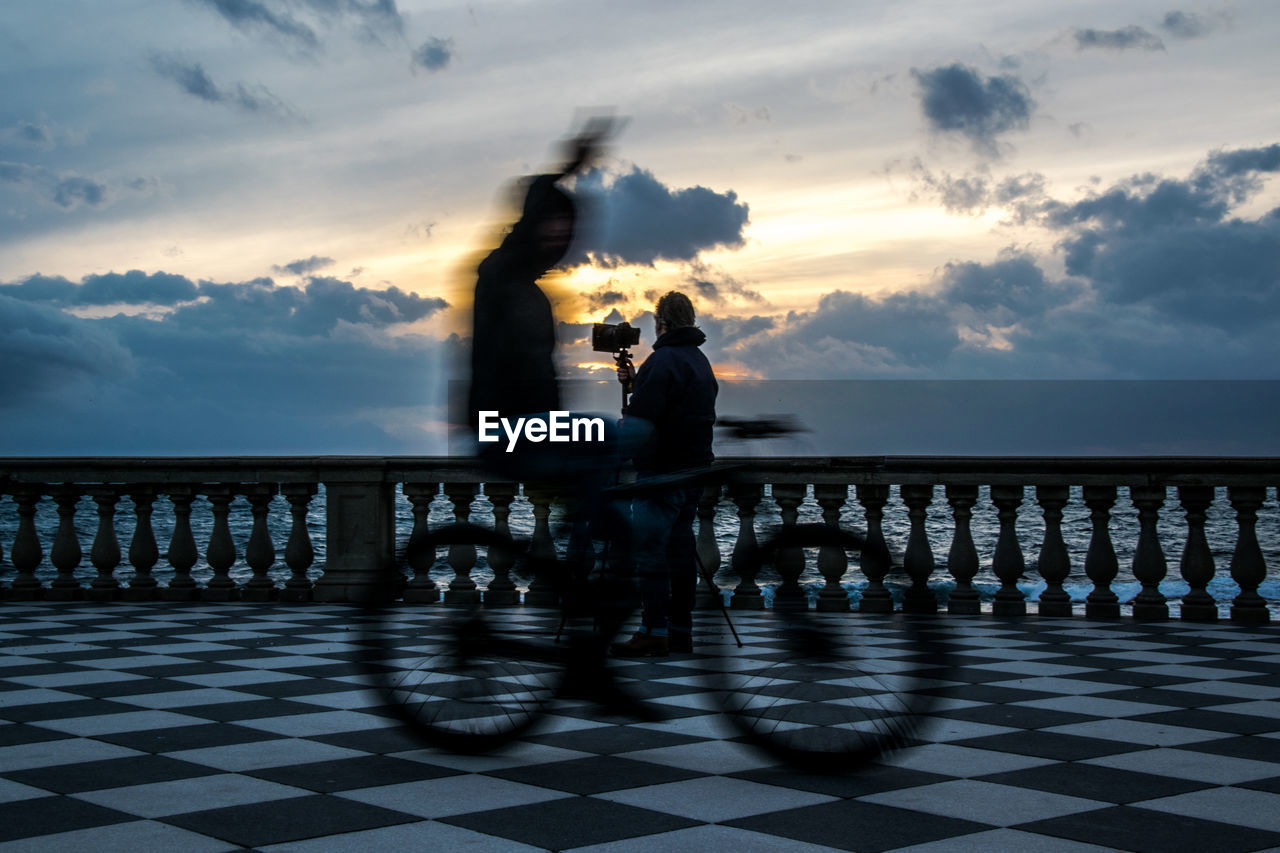 People by sea against sky during sunset
