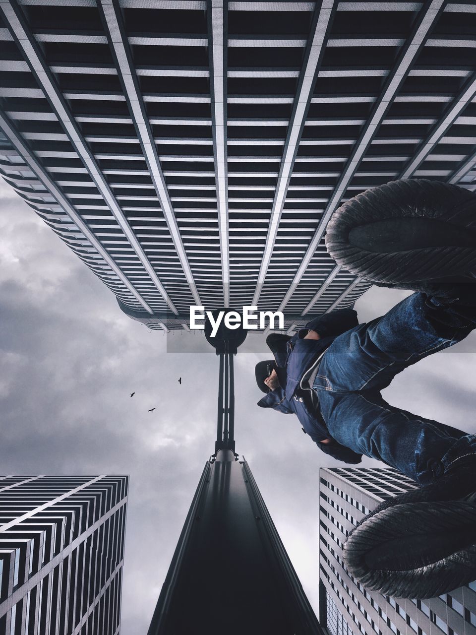 LOW ANGLE VIEW OF MAN ON SUSPENSION BRIDGE