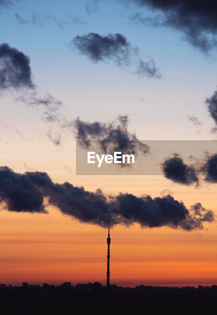 Silhouette of communications tower against cloudy sky