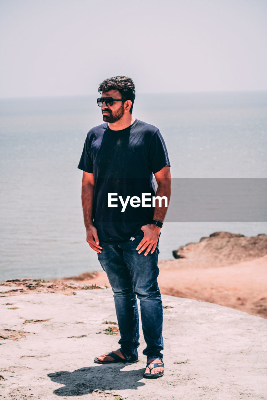 YOUNG MAN STANDING ON BEACH
