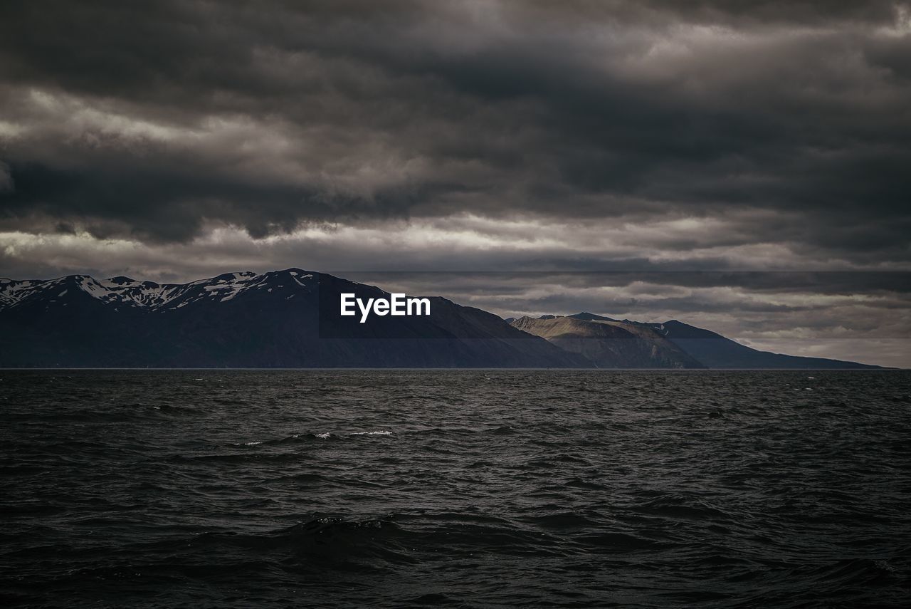 Scenic view of sea against cloudy sky at night