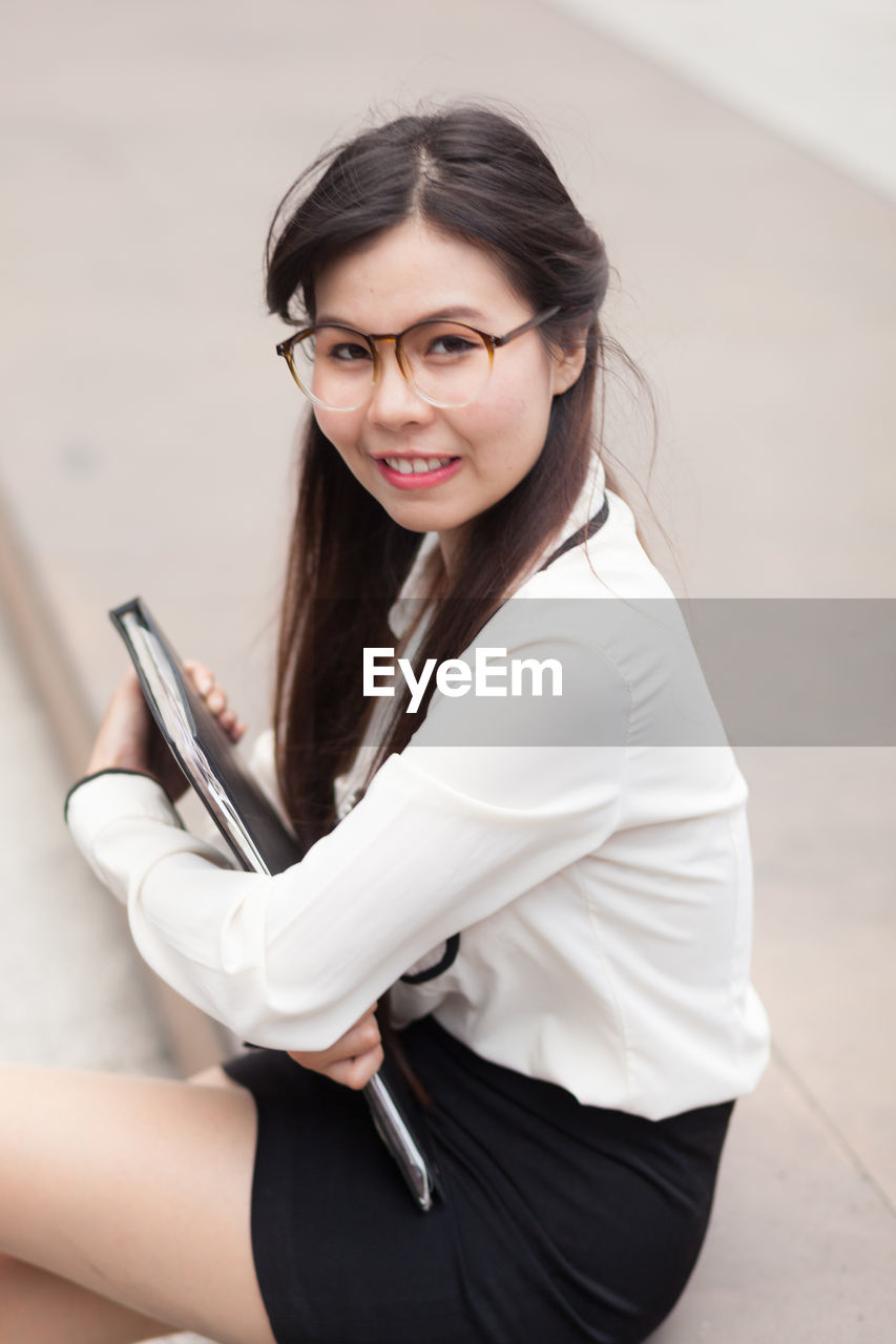 Portrait of young businesswoman with file on steps