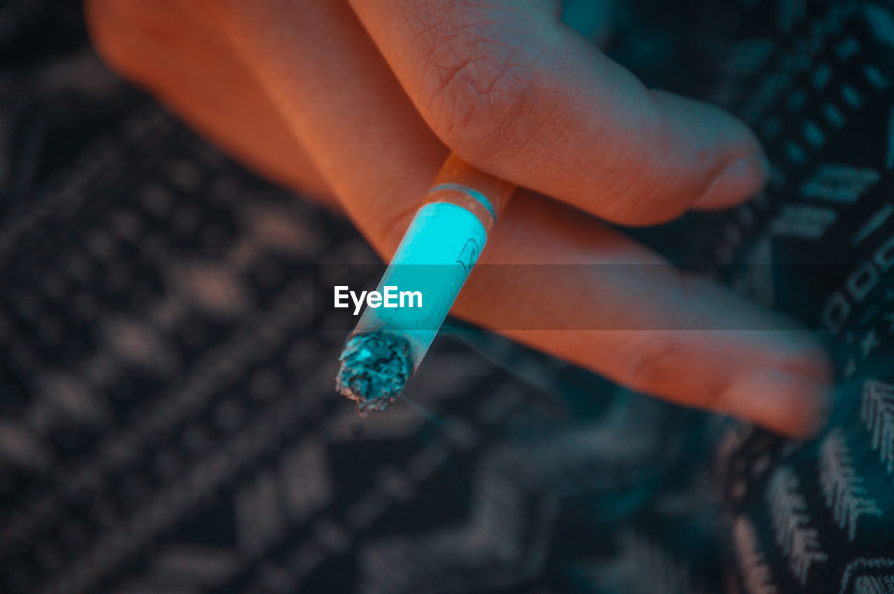 CLOSE-UP OF HANDS HOLDING CIGARETTE