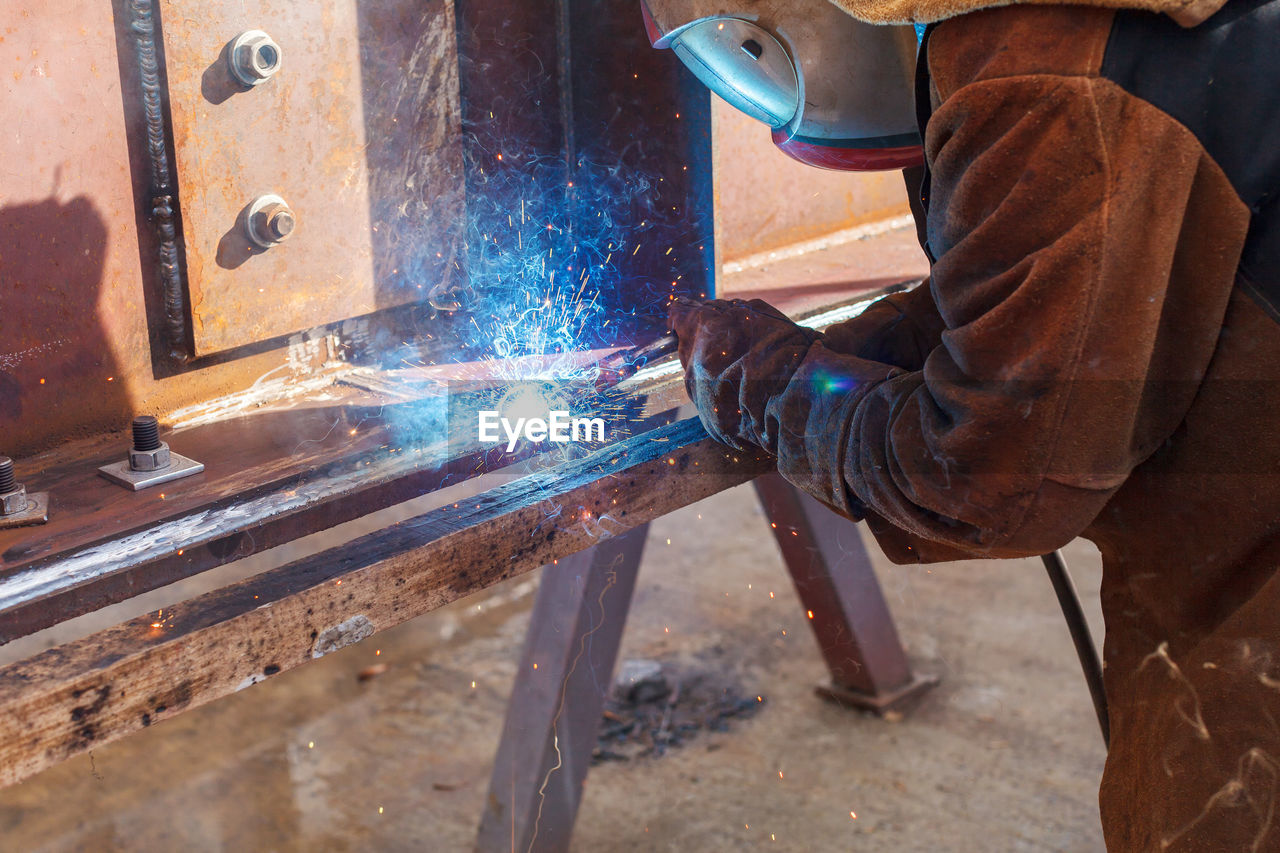 REAR VIEW OF MAN WORKING ON MACHINE