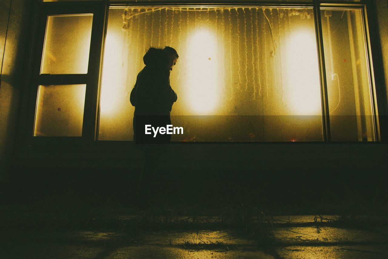 Silhouette of two people dancing against window