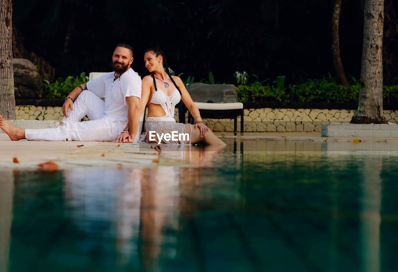 COUPLE SITTING IN SWIMMING POOL