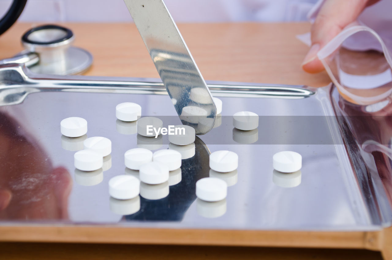 Close-up of doctor by pills on tray