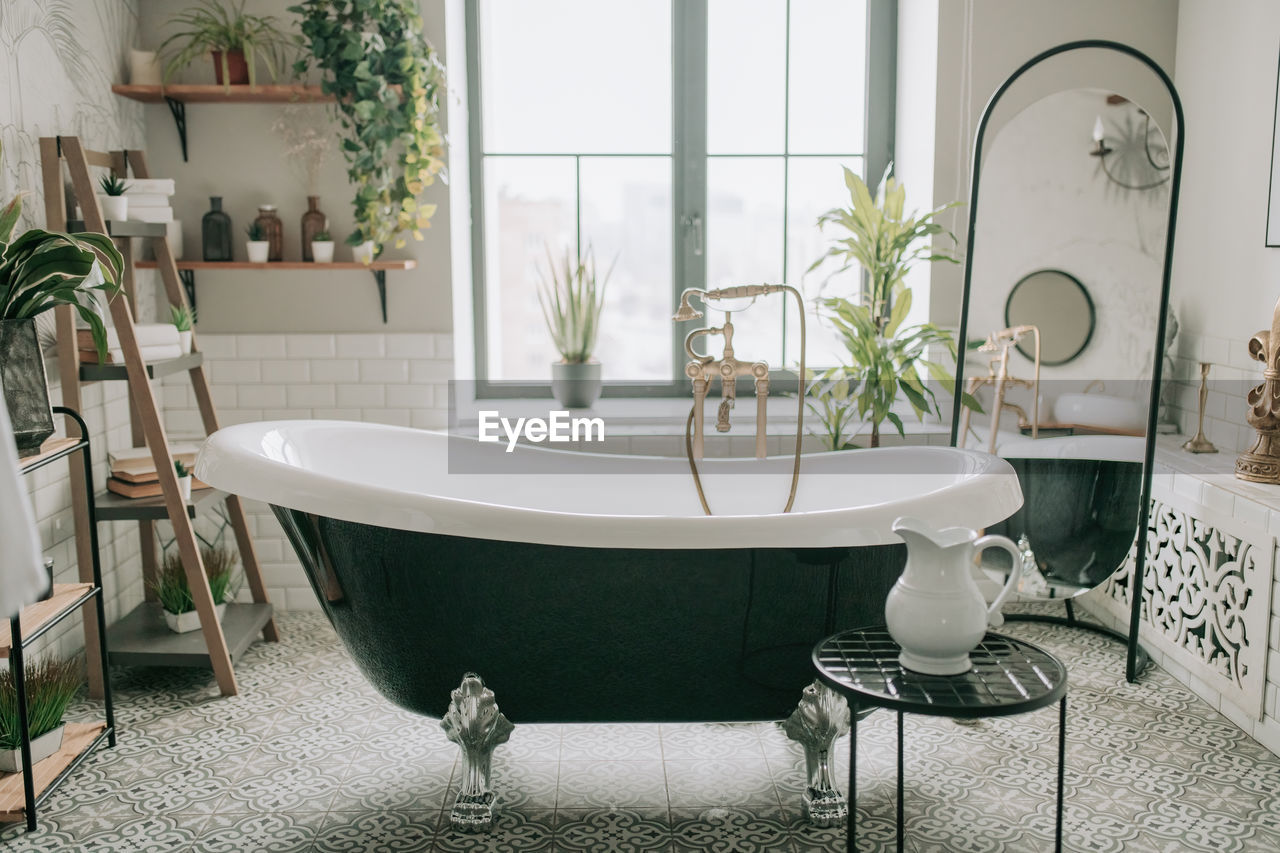 Luxury interior of big bathroom at modern african style with oval bathtub in natural lighting