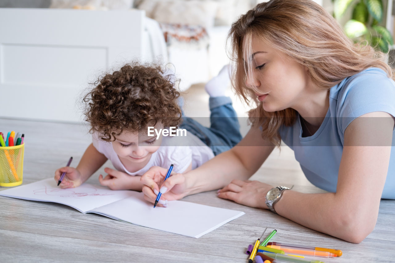 Mother and daughter drawing on book at home