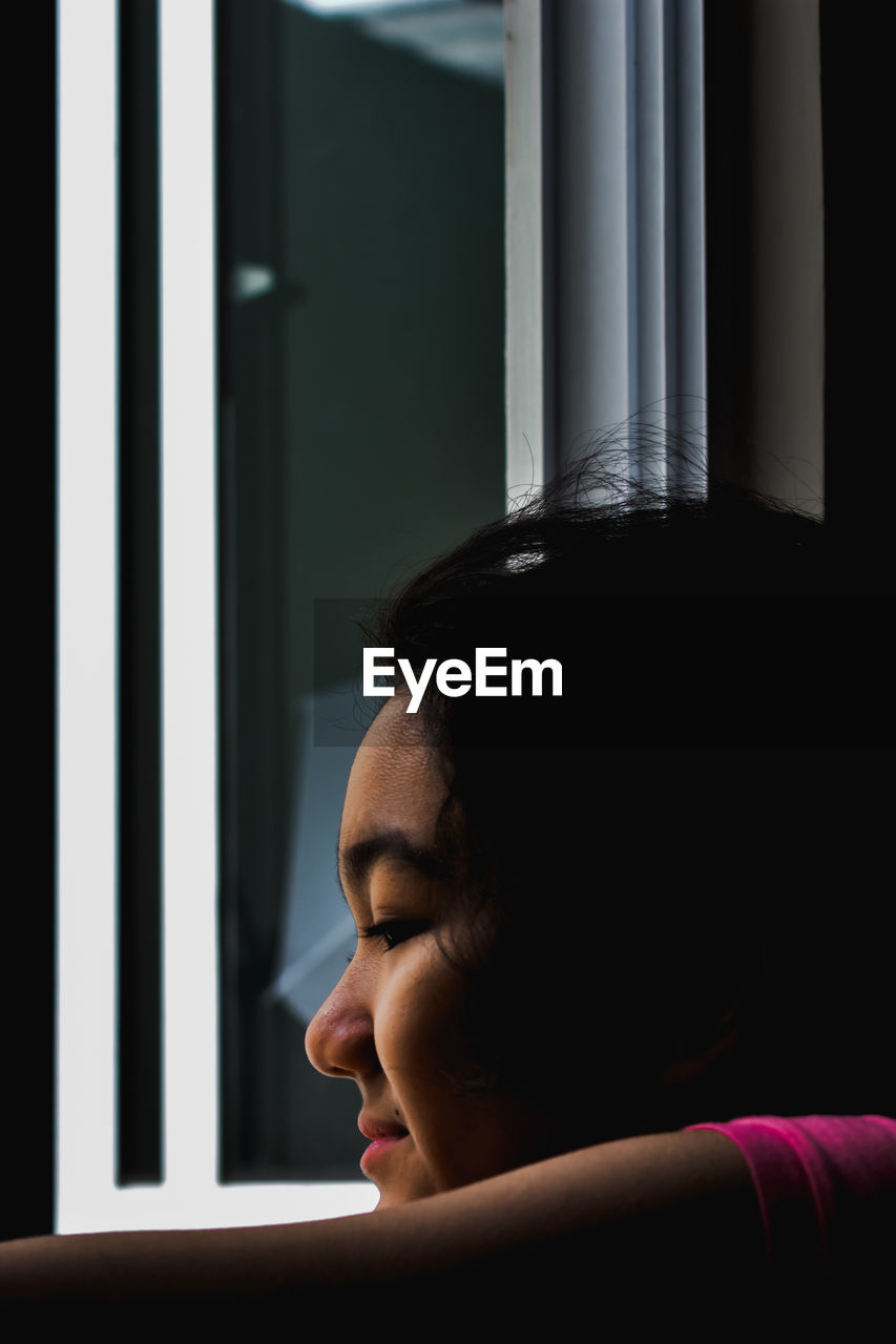 Close-up portrait of a young girl looking out the window