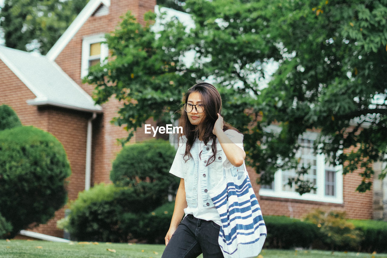 Young woman walking in lawn against houses