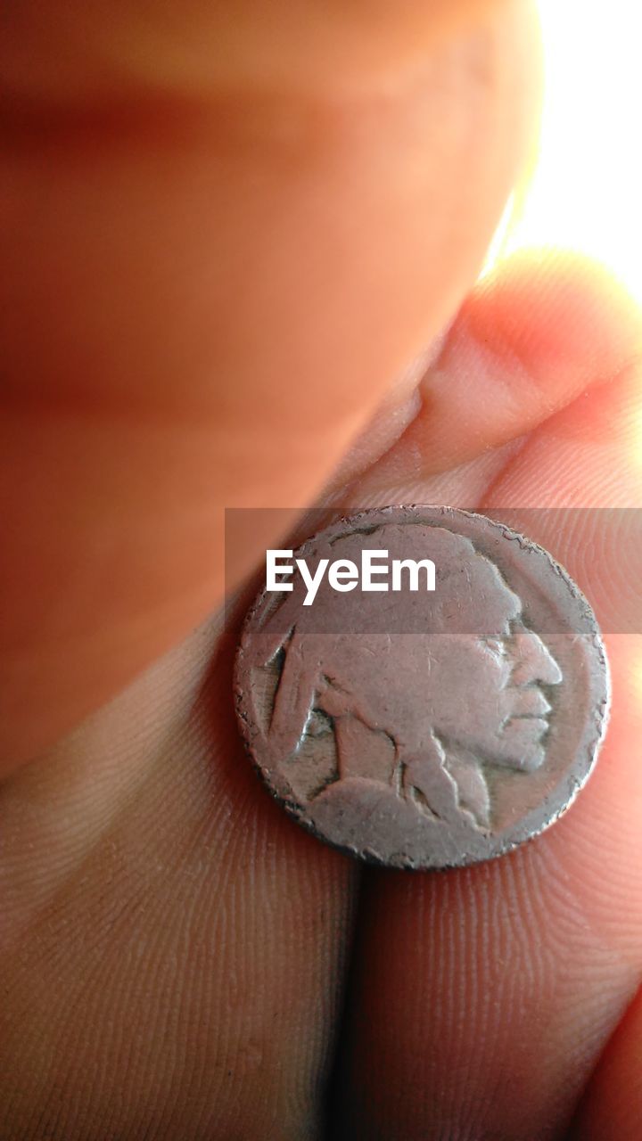 Close-up of cropped hand holding coin