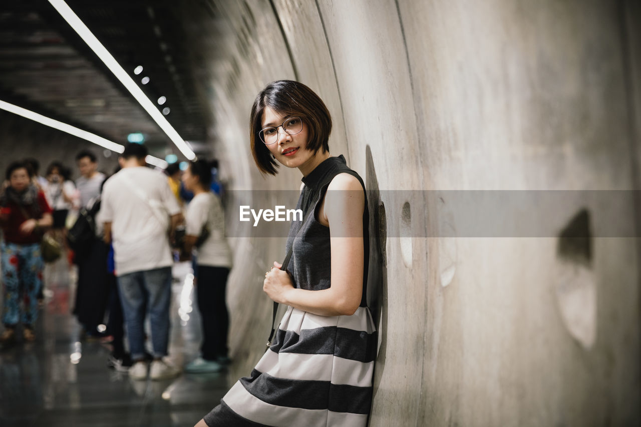 Portrait of asian young short hair beautiful woman wearing glasses and grey dress in tunnel