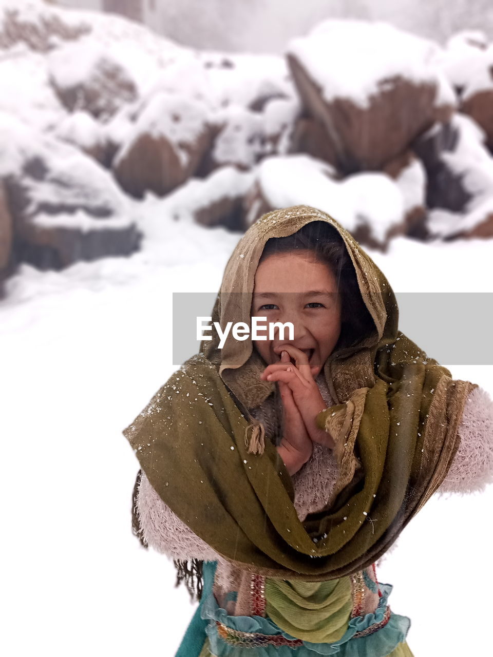 Portrait of smiling young woman sitting on snow covered field