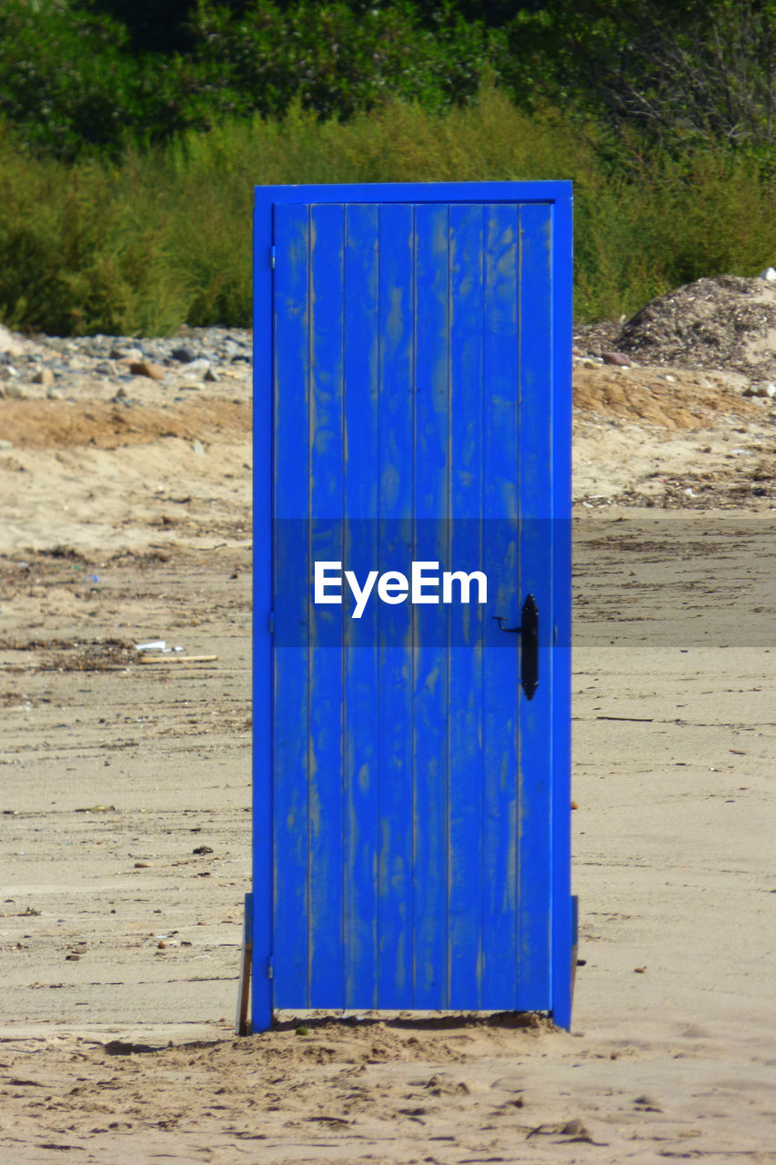 CLOSE-UP OF BLUE CONTAINER ON WOODEN WALL