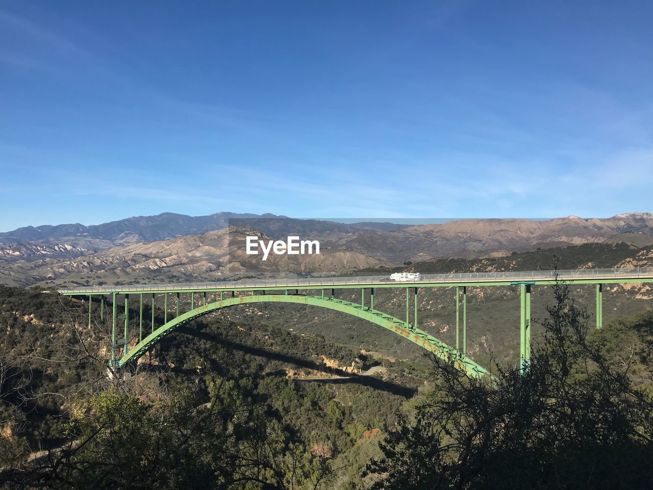 Arch bridge over mountains against blue sky