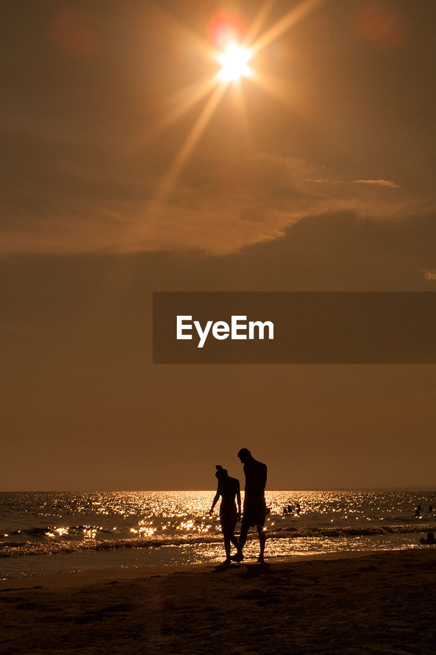 SILHOUETTE PEOPLE STANDING ON BEACH AGAINST SKY DURING SUNSET