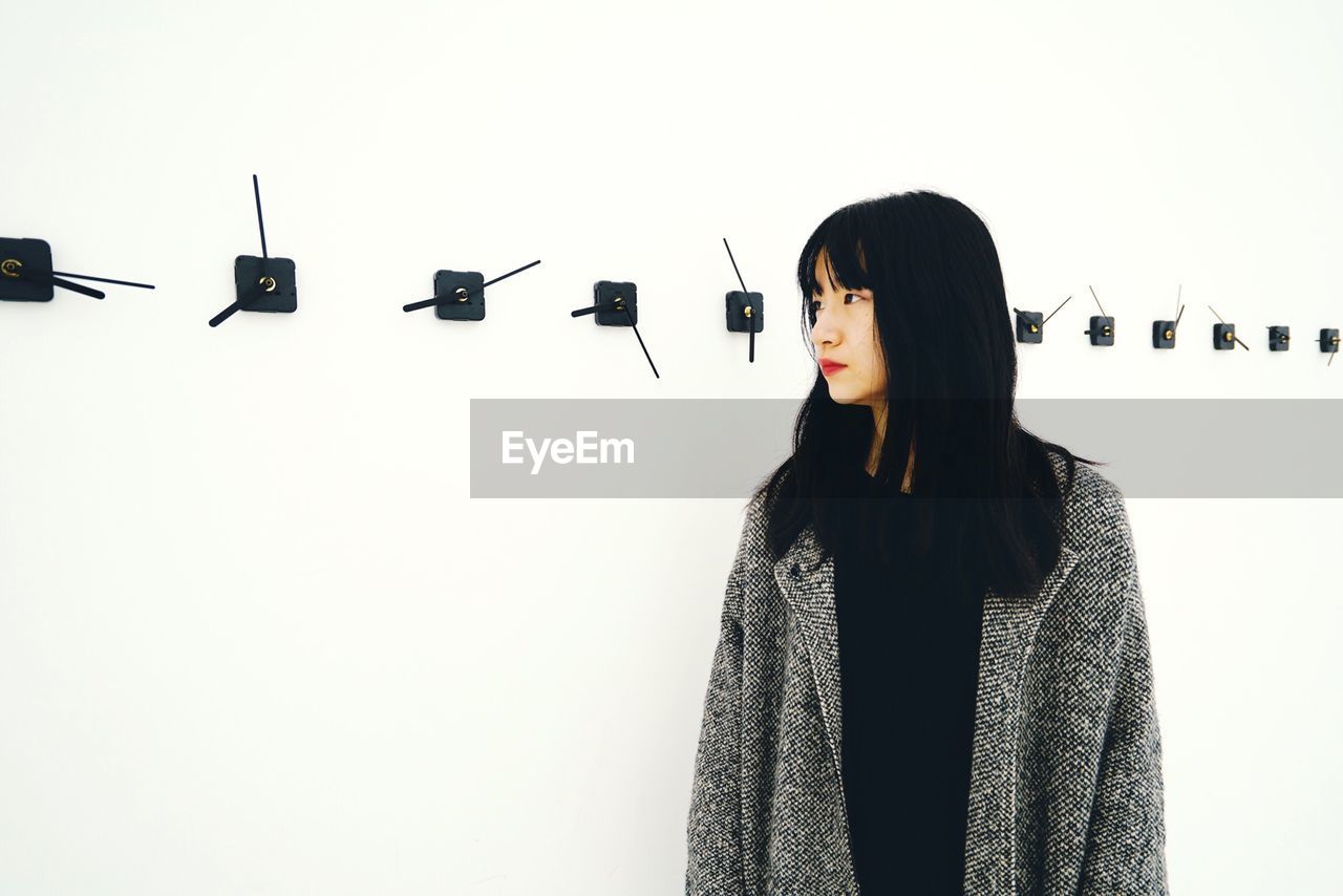 Mid adult woman looking away while standing against wall