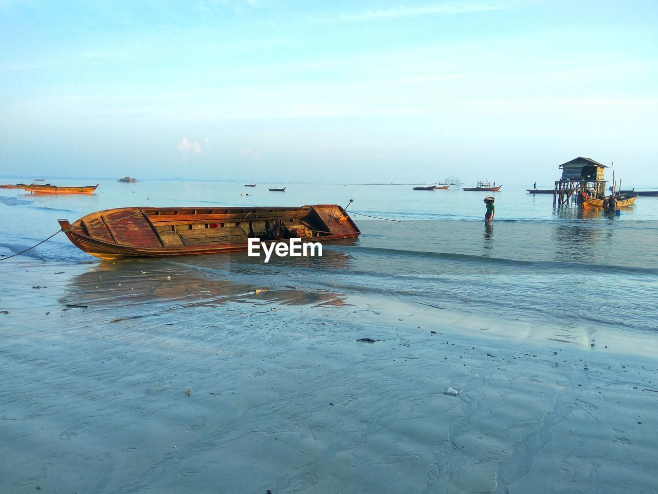 BOATS MOORED ON BEACH AGAINST SKY