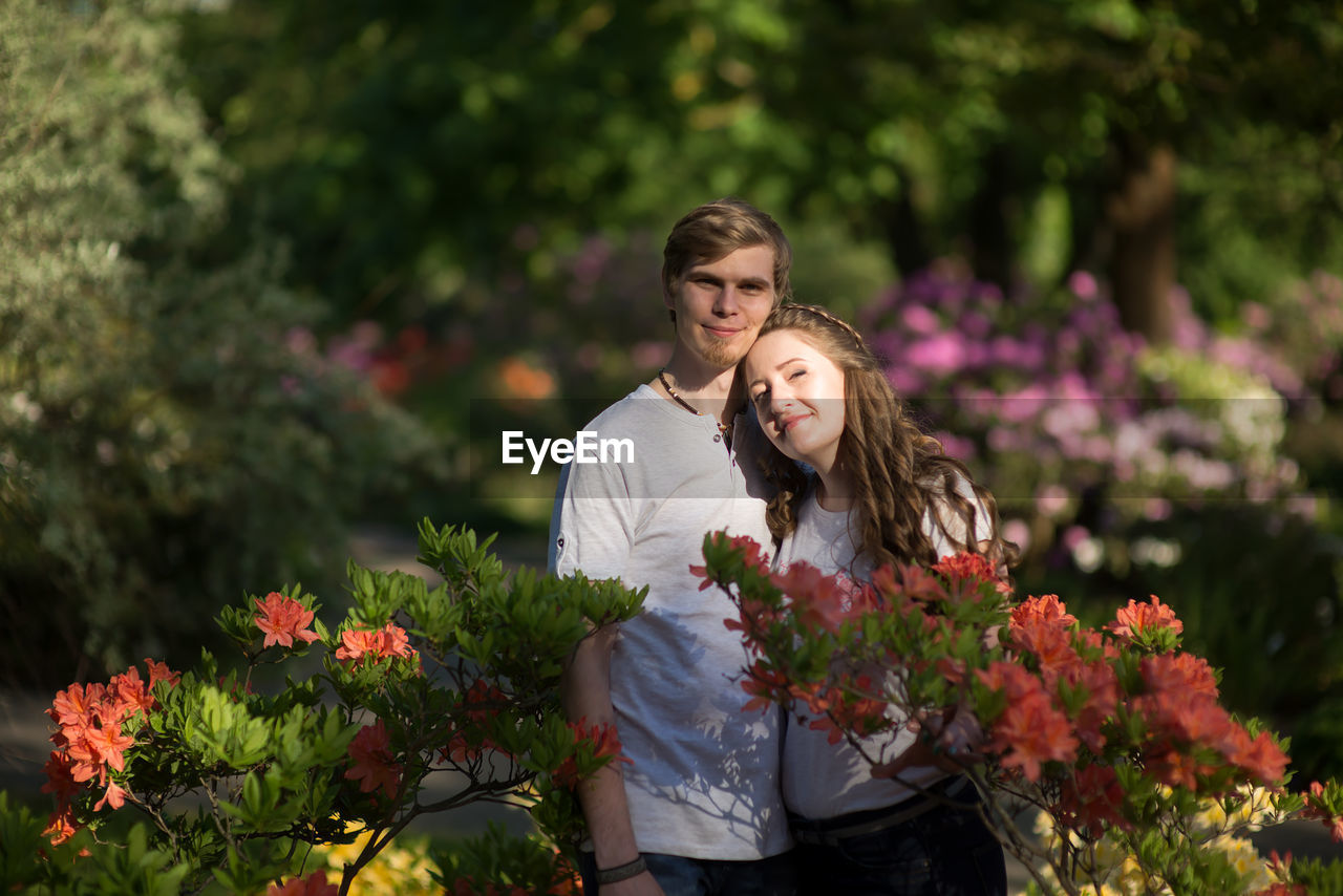 Portrait of couple standing amidst flowers at park