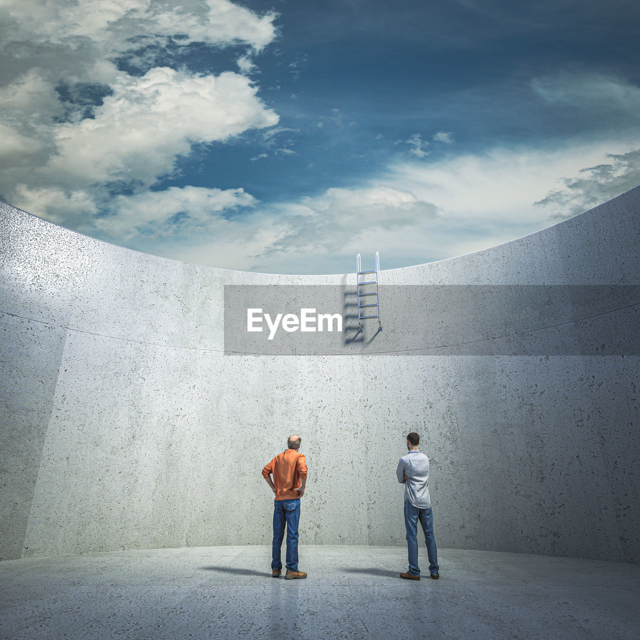 REAR VIEW OF TWO PEOPLE WALKING ON CONCRETE WALL