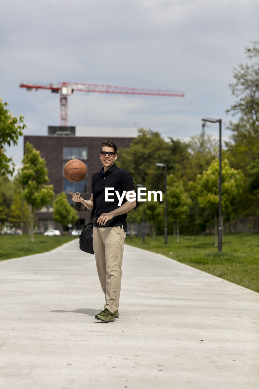 Close-up of mature man throwing basketball while standing outdoors