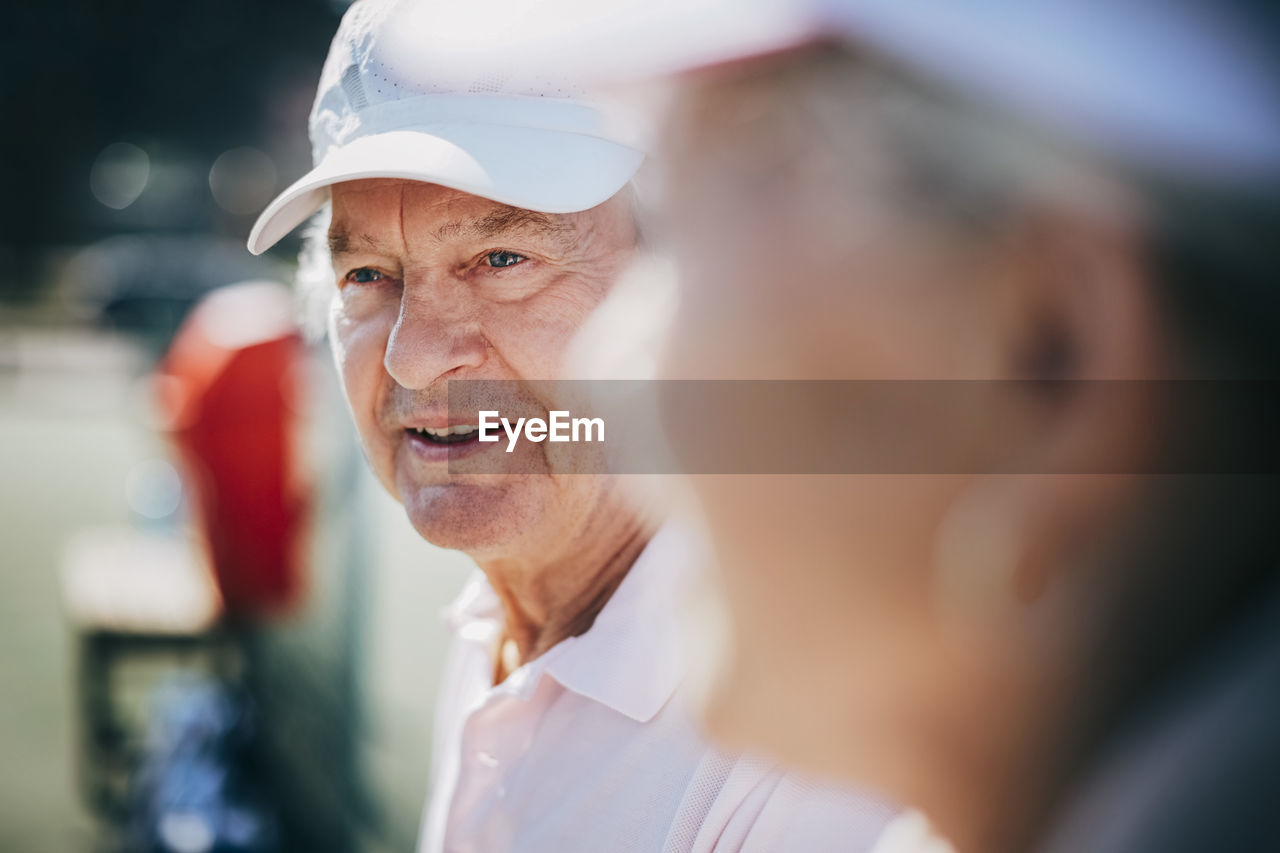 Close-up of senior man with friend at tennis court