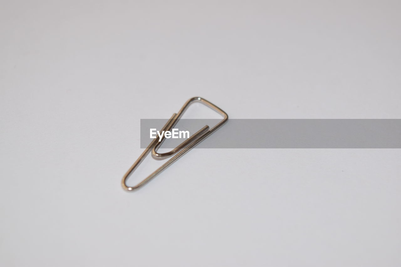 Close-up of metallic paper clip over white background