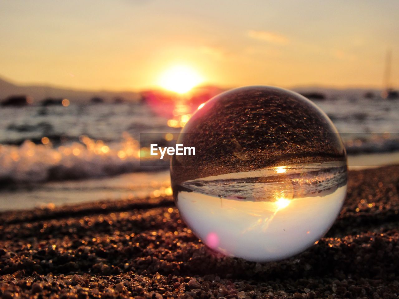 CLOSE-UP OF CRYSTAL BALL ON BEACH AT SUNSET