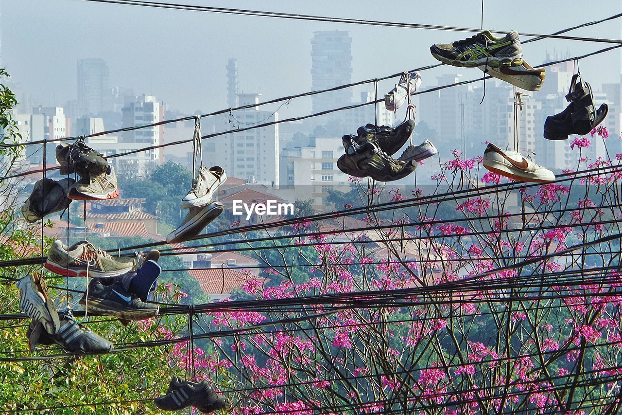 Low angle view of shoes tied on ropes against city