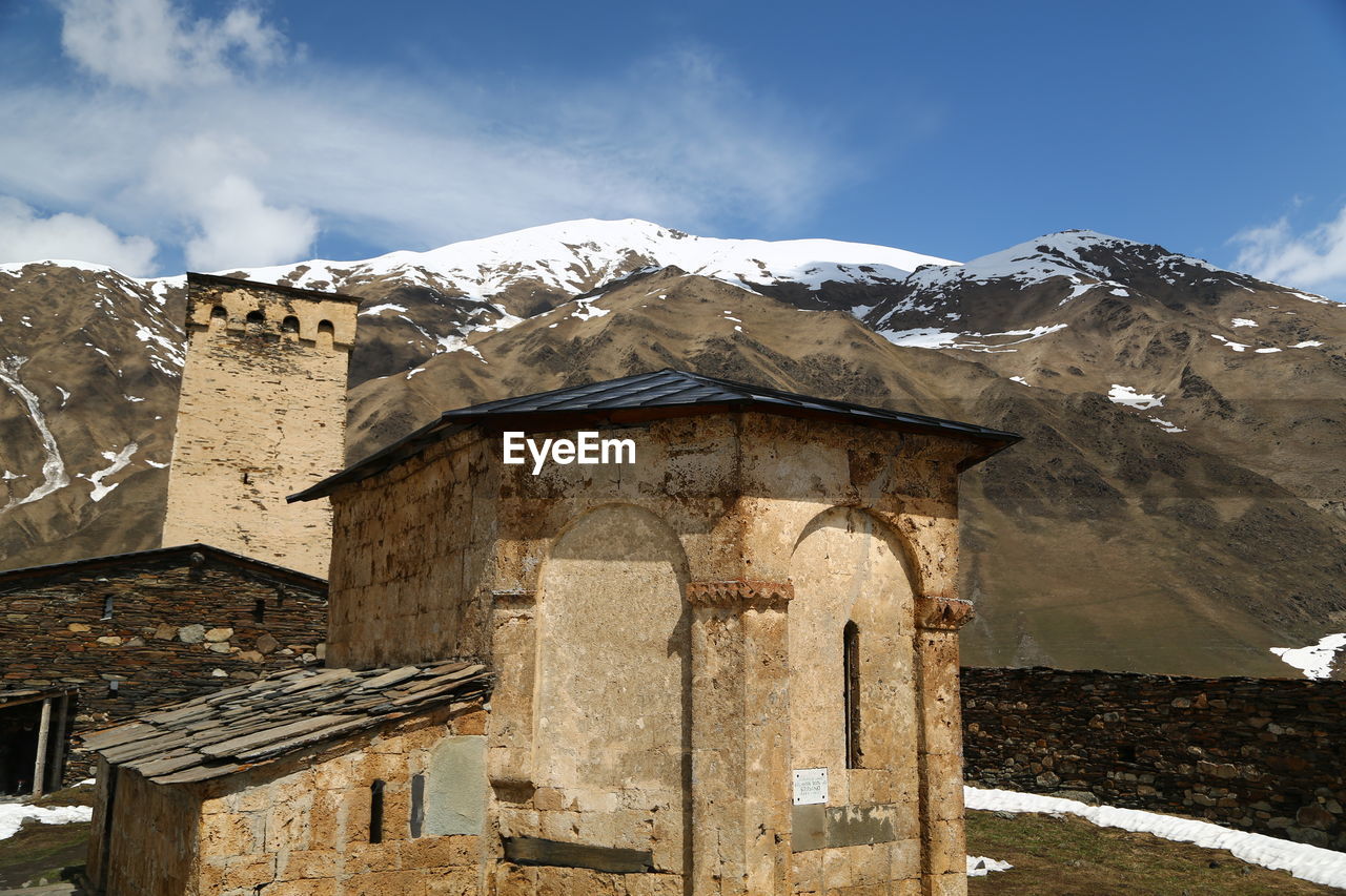 LOW ANGLE VIEW OF OLD BUILDING AGAINST SNOWCAPPED MOUNTAIN