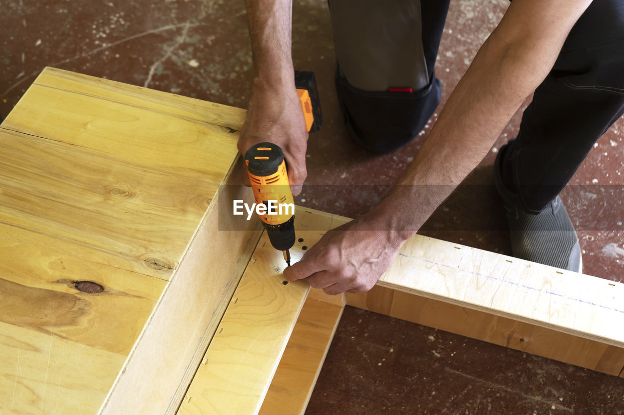 A carpenter screw bolt with an electric screwdriver. assembly furniture service.