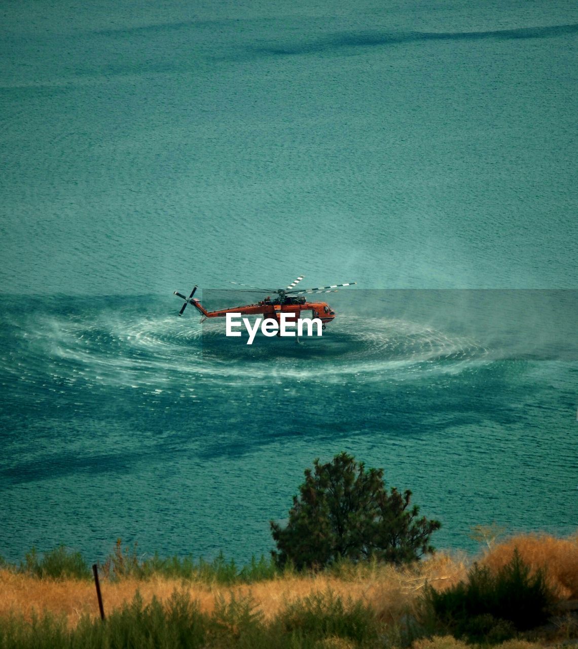 High angle view of helicopter hovering over sea