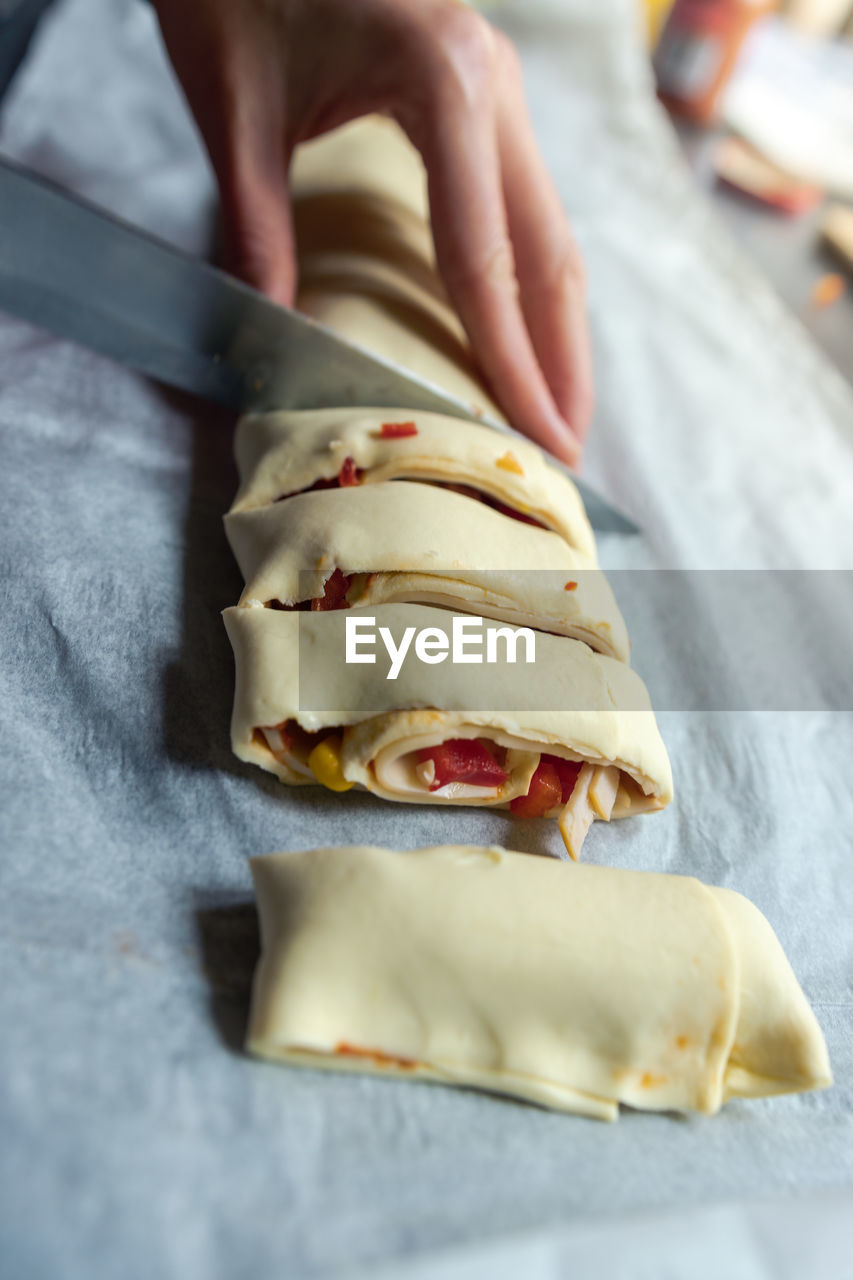 Female hands cut the rolled puff pastry into equal pieces. 