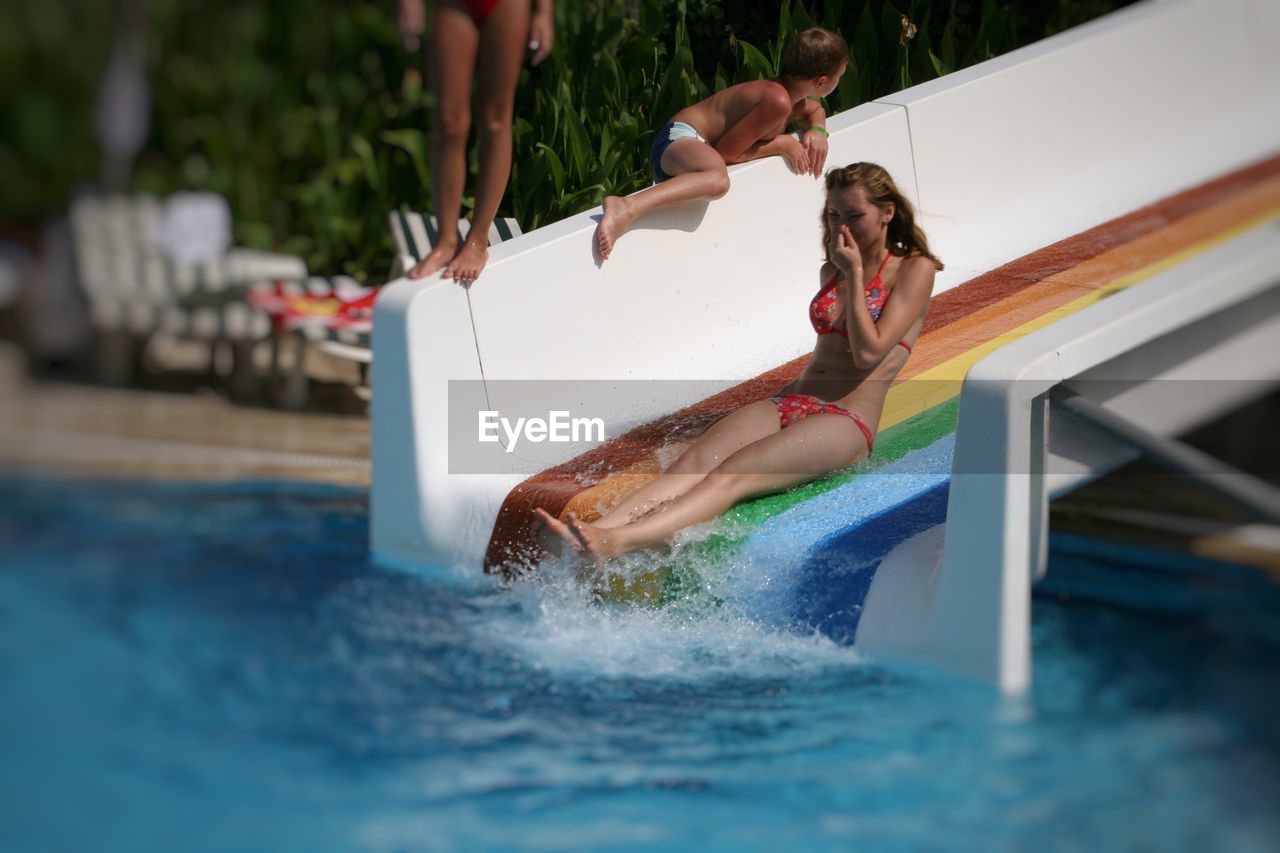 Full length of young woman wearing bikini enjoying on slide at water park