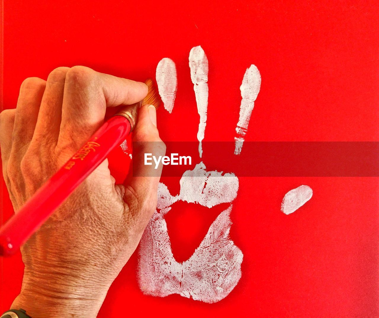 Close-up of hand holding paintbrush for cleaning handprint on wall