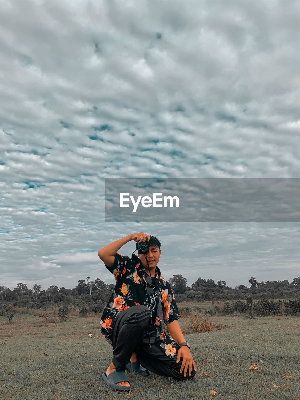 portrait of woman sitting on field against sky