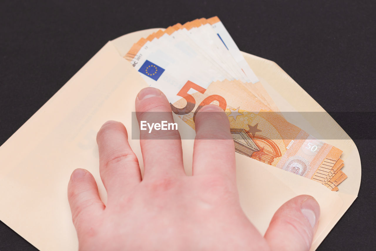 hand, paper currency, finance, currency, business, one person, wealth, studio shot, indoors, finance and economy, paper, close-up, business finance and industry, money, cash, adult, black background
