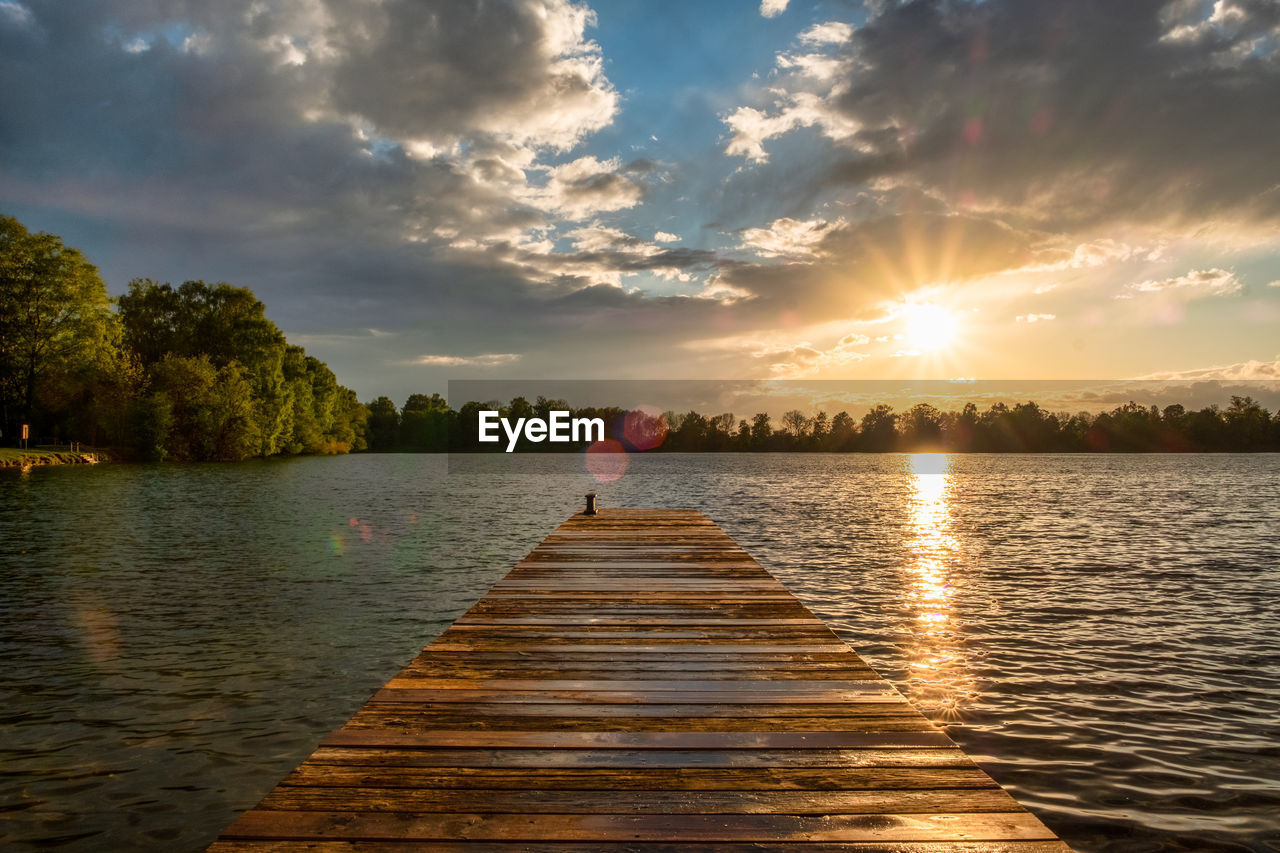 REAR VIEW OF WOMAN ON LAKE DURING SUNSET