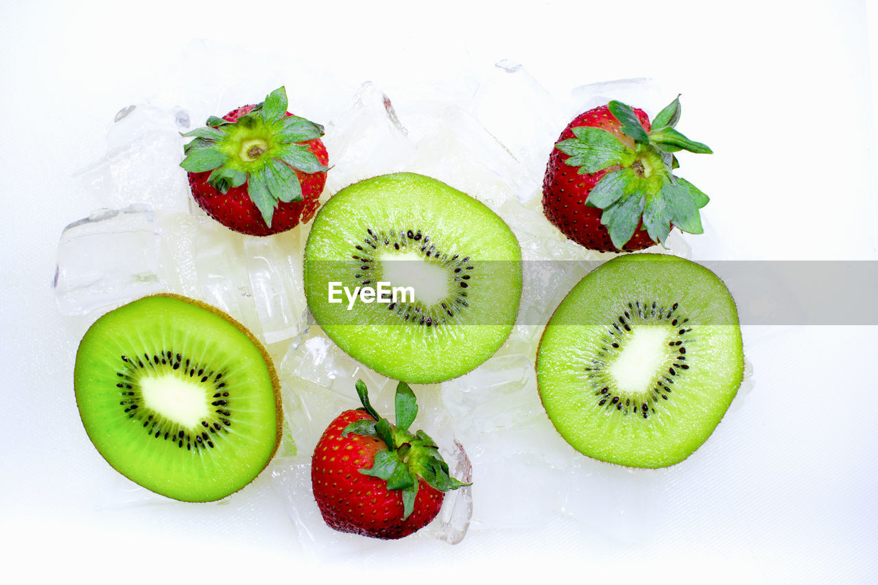 Close-up of kiwis with strawberries on white background