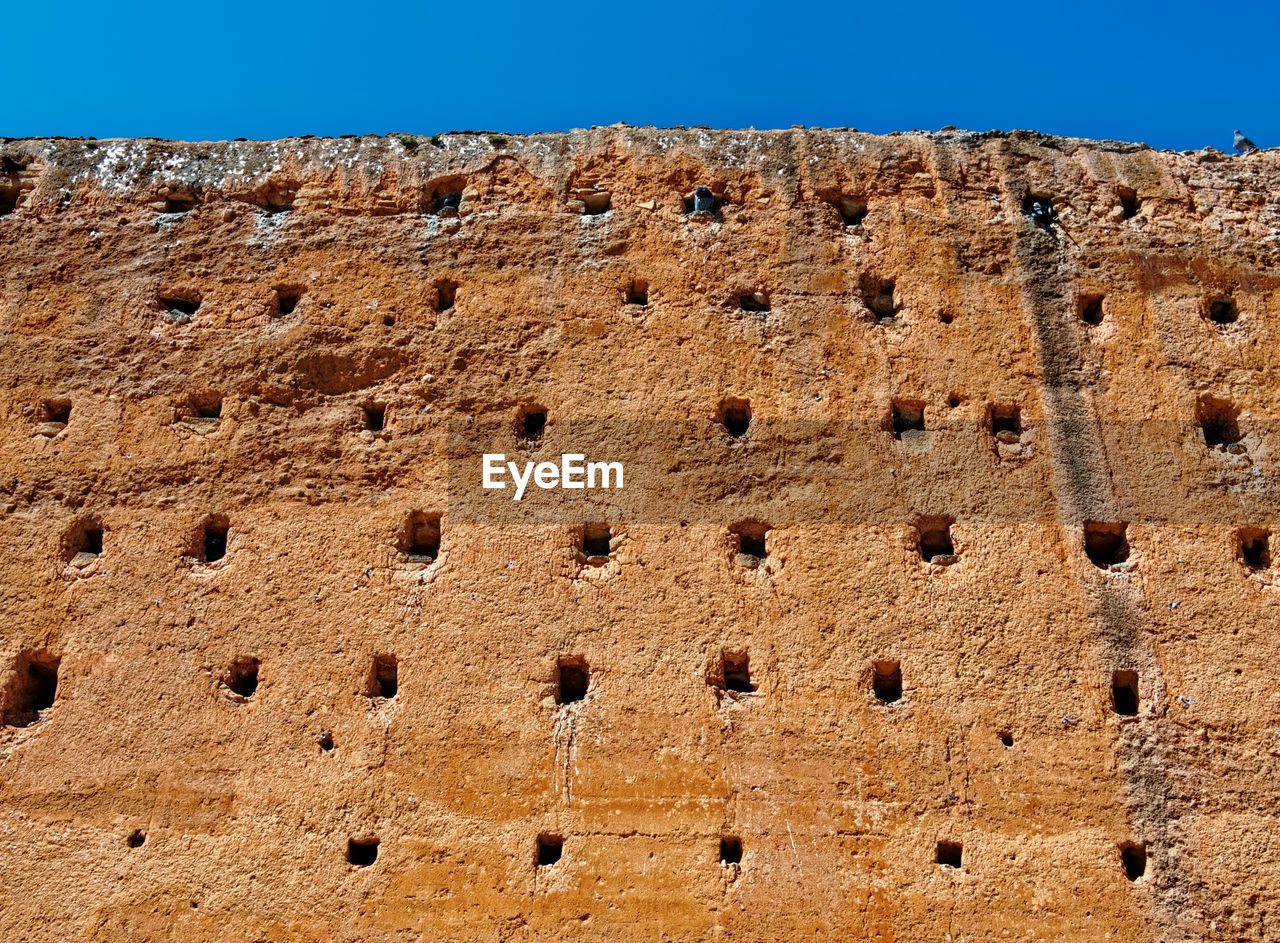 LOW ANGLE VIEW OF WALL AGAINST SKY