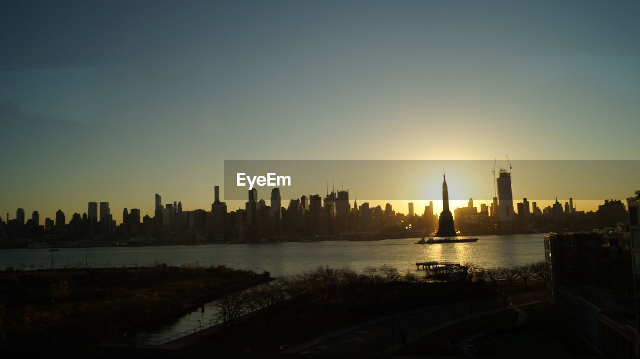 Silhouette buildings in city against sky during sunset