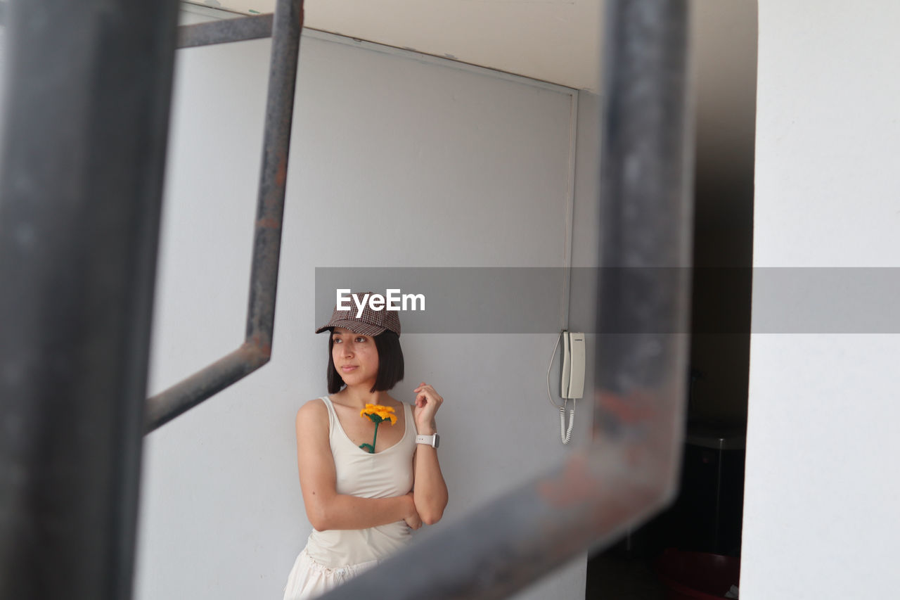 portrait of young woman using mobile phone while standing at home