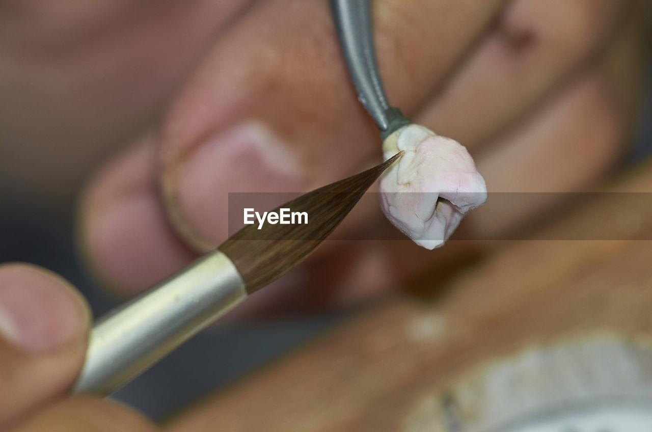 Close-up of hand using paintbrush on tooth