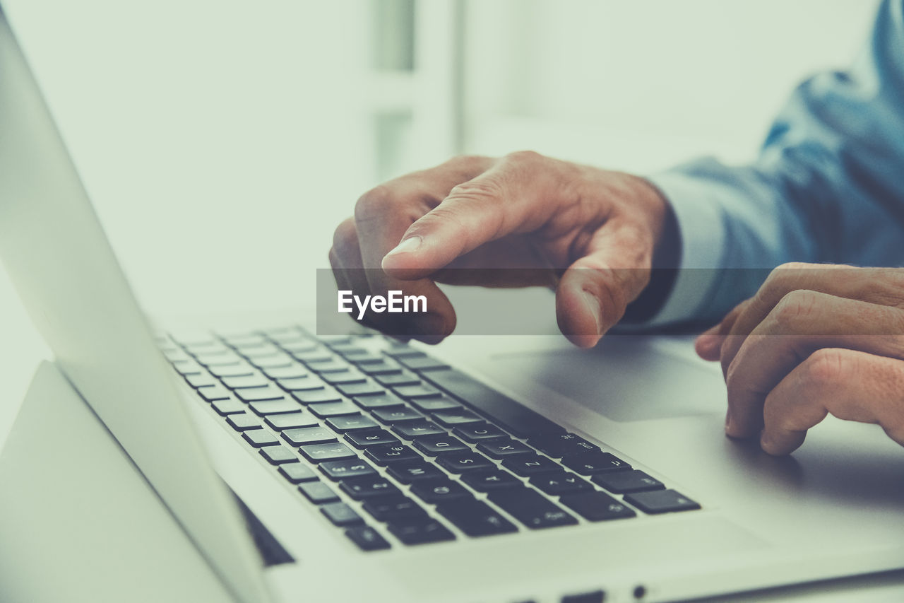 Closeup man hands typing on computer keyboard. businessman using laptop at home. office workplace