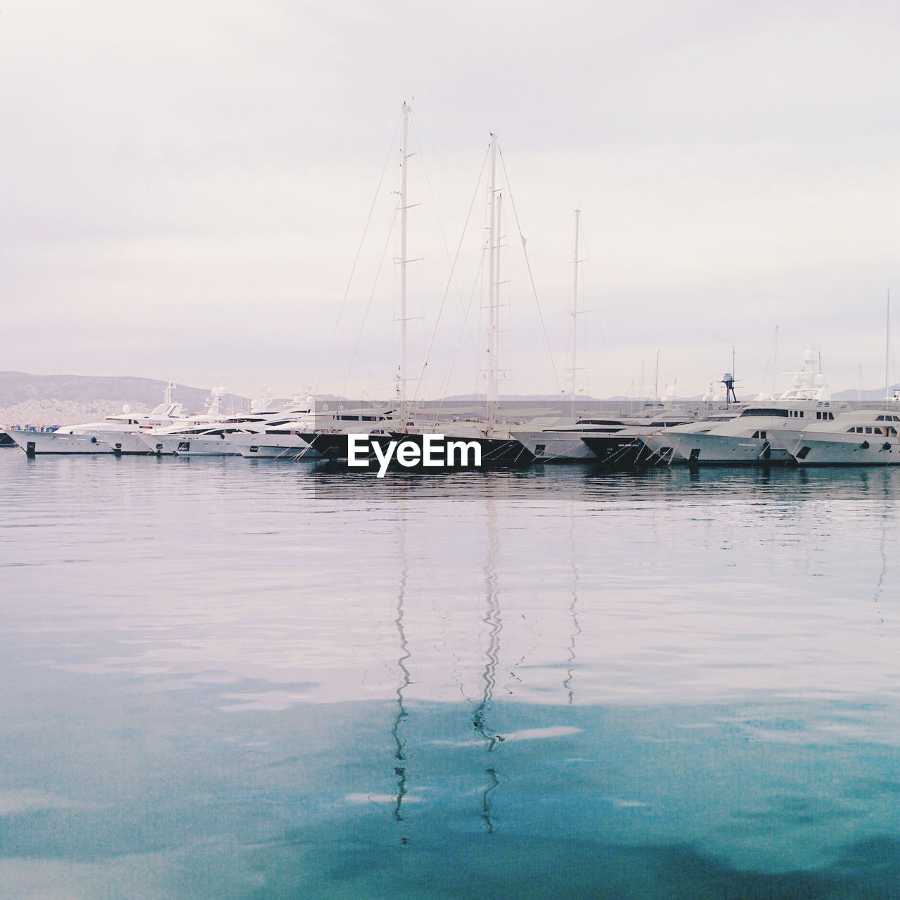 Sailboats moored in sea against sky