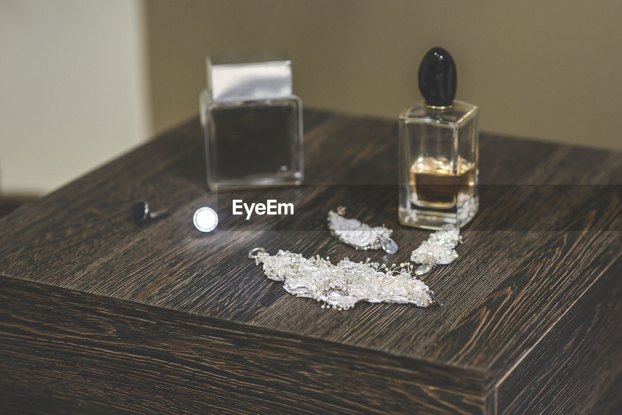 High angle view of jewelry with perfume spray on wooden table