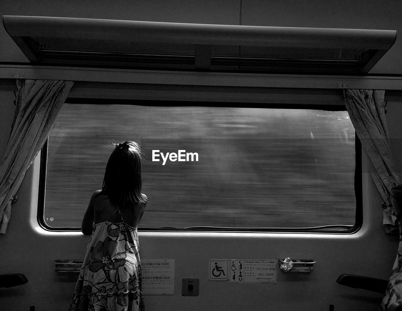 Rear view of girl looking through window while traveling in train