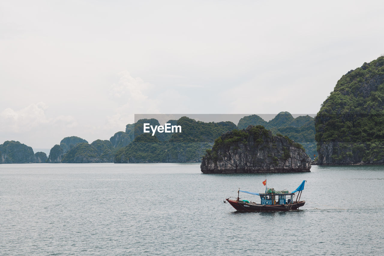 Fishing boat on halong bay by mountain