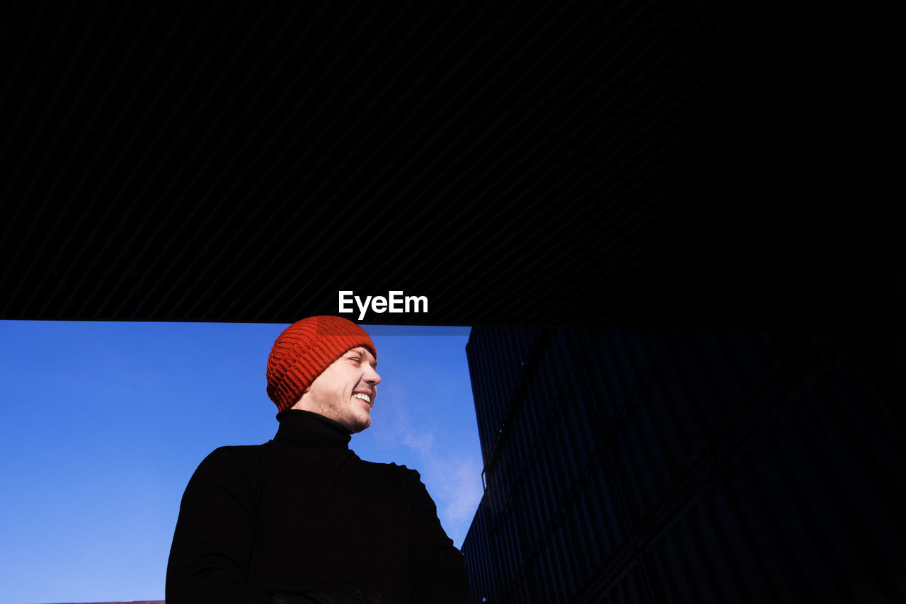 Low angle view of smiling man standing in city